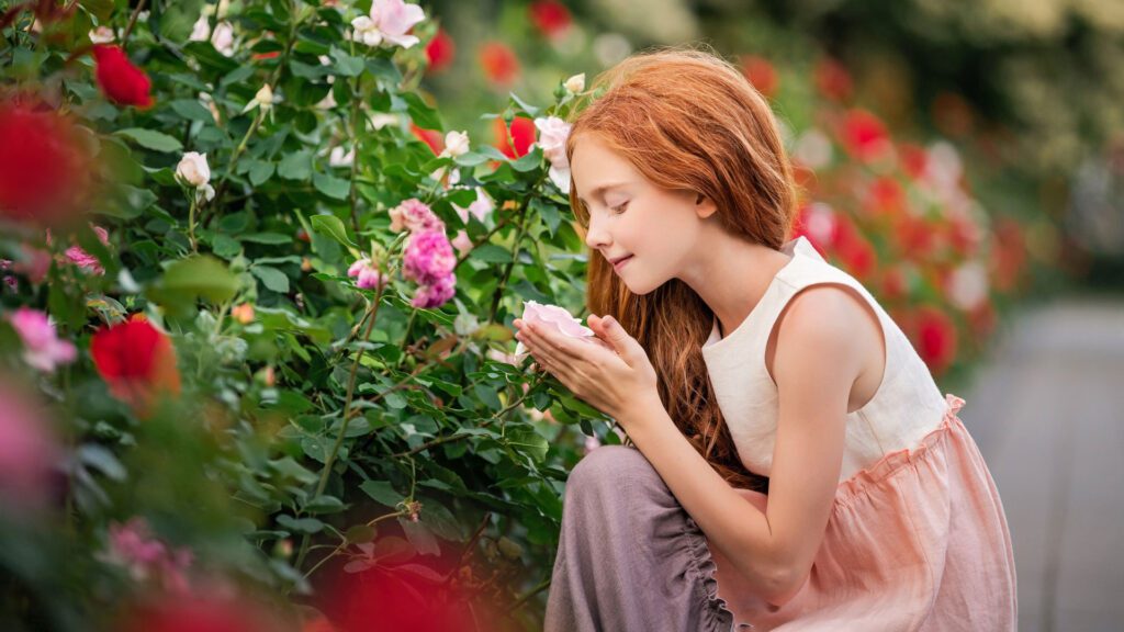 girl smelling flowers in garden