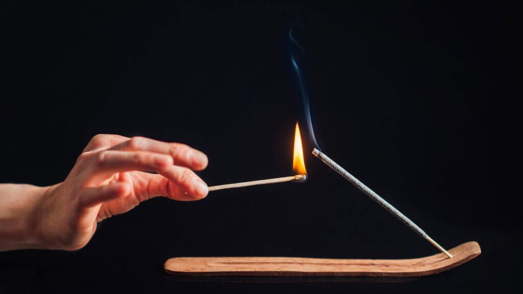 lighting incense stick with burning match stick
